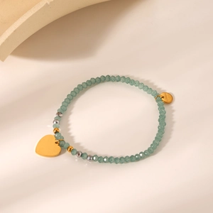 Detail of beaded bracelet with green natural stones and stainless steel heart charm
