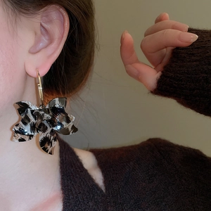Detail of model wearing large leopard print resin flower C-shaped hoop earrings