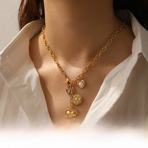 Detail of gold multi-pendant necklace featuring red heart gem and sunflower charms