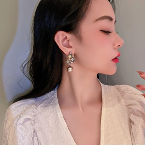 Close-up of vintage flower earrings with faux pearls and crystals on a model