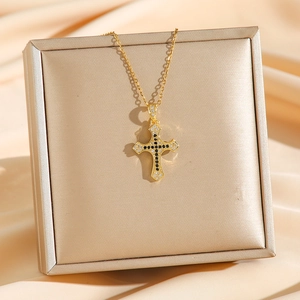 Gold plated cross necklace with black and white pavé cubic zirconia on a luxury jewelry box