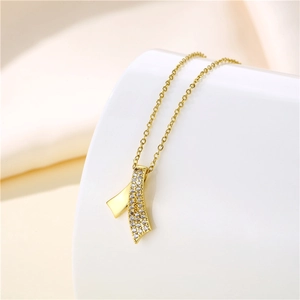 Detail of gold ribbon pendant necklace featuring cubic zirconia on elegant ceramic stand