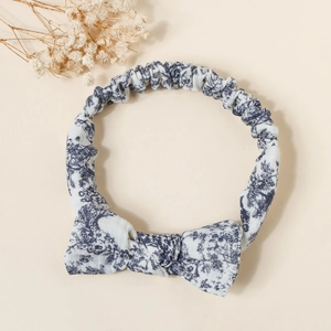 Detailed view of elastic cotton baby headband with blue floral bow on beige background