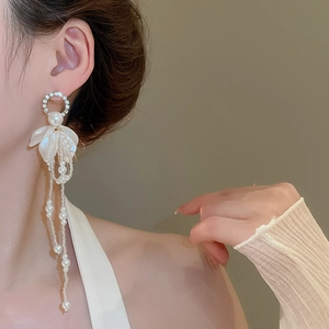Close-up of floral tassel earrings featuring pearls and sparkling rhinestones on model