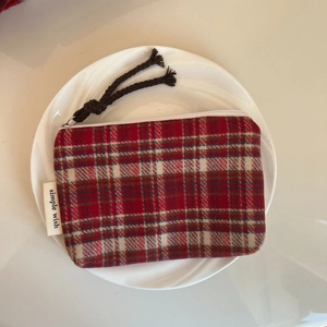 Detail of red and white plaid coin purse featuring a zip puller and woven brand tag