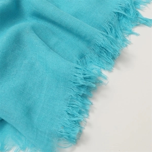 Close-up of light blue linen cotton scarf featuring delicate frayed fringe edges