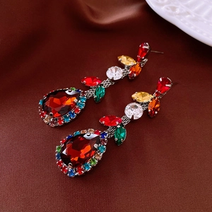 Macro shot of bohemian crystal teardrop earrings on luxury red silk background