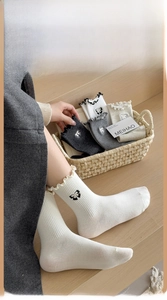 Close-up of knit crew socks with embroidered bow details and lettuce edge cuffs