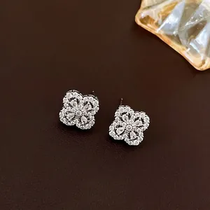 Elegant silver flower stud earrings with sparkling cubic zirconia on a leather background