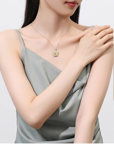 Close-up of a square yellow gemstone pendant with silver halo setting on a model