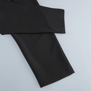 Detailed close-up of the black trousers leg hem showing precision stitching and fabric