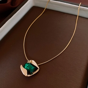 Detail of emerald-cut green gemstone pendant with gold snake chain in a gift box