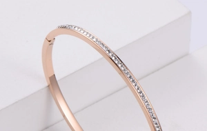 Detailed macro view of a rose gold zircon bracelet on a white geometric stone