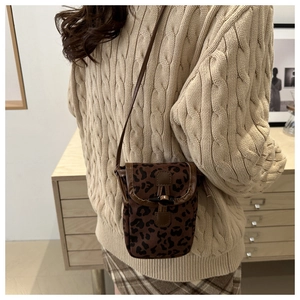 Detail of leopard print crossbody bag with horn buckle closure on knit sweater