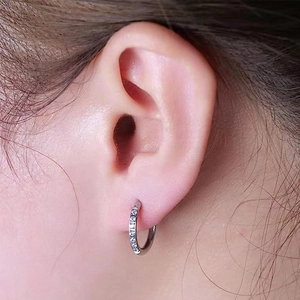 Detailed close-up of a silver hoop earring featuring micro-set zircon stones on the ear