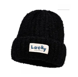Detail of black woolly knit beanie with white Lucky label and soft curly texture