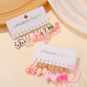 Gros plan de boucles d'oreilles panda et cerise sur un plateau à bijoux en bois