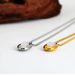 Detail of oval shell pendants in gold and silver finish with translucent white gemstones