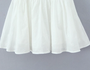 Detail of white Broderie Anglaise floral embroidery on the hem of a mini dress