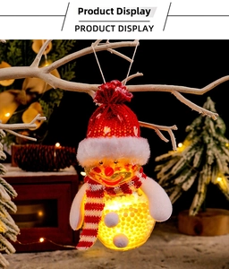 Close-up of a glowing glass snowman ornament with red hat on a festive tree