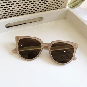 Detail of retro oval nude beige frames with brown gradient lenses on a white tray