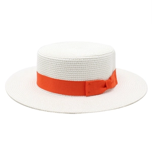 Detail of white straw boater hat featuring a vibrant orange ribbon bow and dense weaving