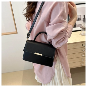 Détail d'un sac à bandoulière en cuir noir avec boucle dorée et poignée supérieure