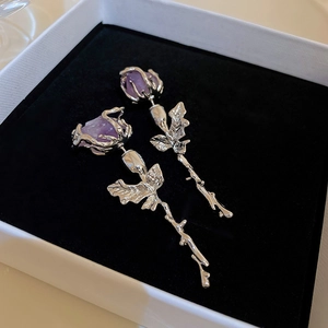Close-up of silver rose earrings with purple crystals and artistic stem details
