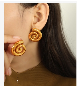 Vue macro de boucles d'oreilles spirales dorées montrant la texture sur un modèle