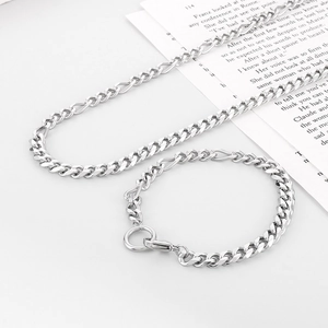 Polished stainless steel Cuban chain necklace and bracelet set on a white book background