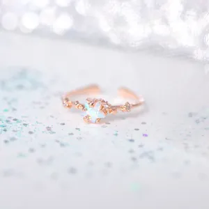Macro detail of 18K gold star ring with aurora opal stone and adjustable open band