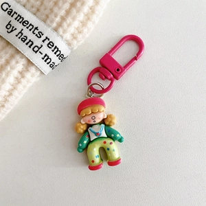 Close-up of cute cartoon girl keychain with pink hook on soft knit background