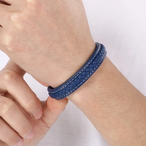 Détail d'un bracelet en cuir tressé bleu avec coutures blanches sur un poignet