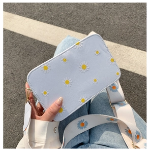 Detail of light blue floral embroidered crossbody bag with a wide strap and gold buckle