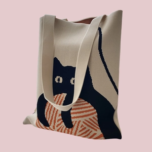 Detail of knitted tote bag featuring a cute black cat and orange yarn ball design