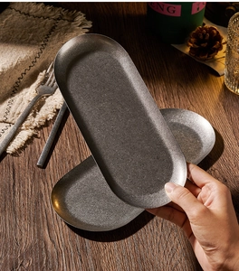 Detailed texture of gray vintage oval 304 stainless steel snack plates on a wooden table