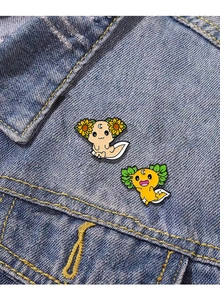 Dettaglio di simpatiche spille in smalto con motivi a girasole e luna su giacca di jeans