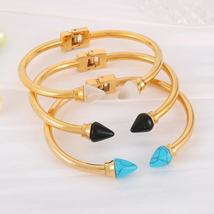 Detailed stack of gold stainless steel arrow bracelets with white, black, and blue accents