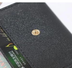 Close-up of black glitter faux leather wallet featuring a round golden snap button closure