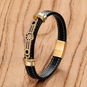 Détail du bracelet en cuir tressé noir avec fermoir fleur doré et cristaux sur bois