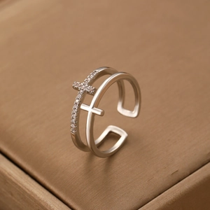 Macro detail of silver double-layer cross ring featuring white zircon and polished finish