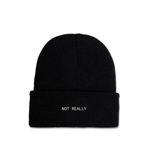 Detail of NOT REALLY white embroidery on a black ribbed knit beanie hat for winter