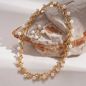 Elegant gold leaf vine jewelry set with white pearls and crystals on a stone base