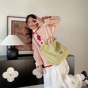 Detailed view of large retro striped plush handbag worn by model in casual outfit