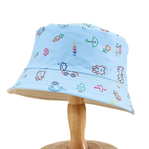 Light blue kids bucket hat with colorful cartoon patterns and happy prints on wood stand