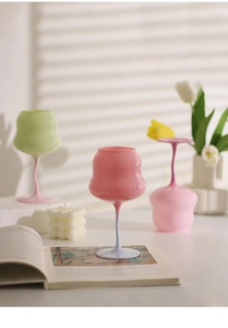 Detail of pink crystal wine glass with light blue stem on open book with shadows