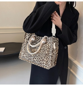 Leopard print canvas tote bag with detachable strap shown on shoulder with black coat