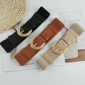 Dettaglio di tre cinture elastiche larghe in nero, marrone e beige con fibbie dorate