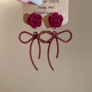 Détail de boucles d'oreilles fleur en velours rouge vintage avec glands à nœud