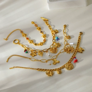 Detail of 18K gold-plated stainless steel bracelets with charms like stars and flowers